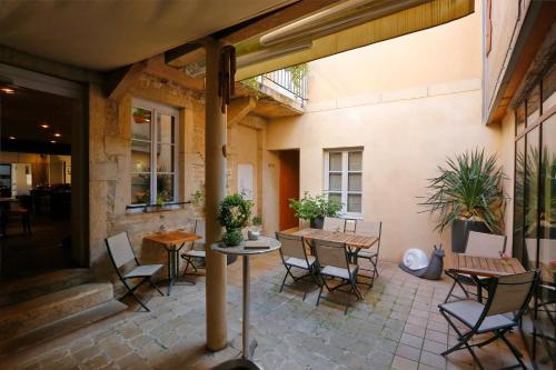 eine Terrasse mit Tischen und Stühlen und ein Gebäude in der Unterkunft The Originals Boutique, Hôtel de la Paix, Beaune (Qualys-Hotel) in Beaune