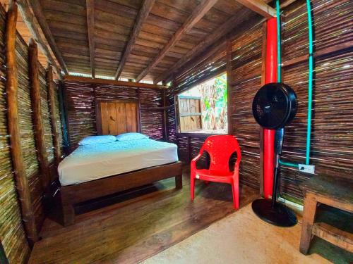 a small bedroom with a bed and a red chair at The Humpback Turtle in El Valle