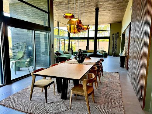 une salle à manger avec une grande table et des chaises en bois dans l'établissement MAISON CHAPRON Villa de standing avec piscine, calme et golf à Biscarrosse, à Biscarrosse