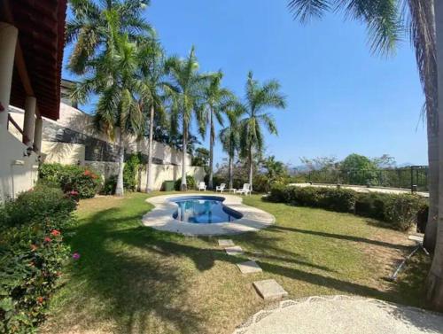 a small pool in the middle of a yard with palm trees at Estudio con WiFi, Netflix y Aire in Ixtapa