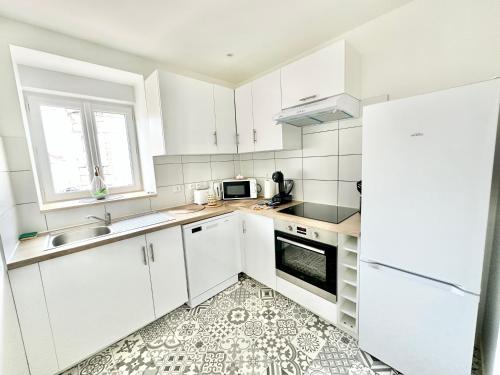 une cuisine blanche avec des armoires blanches et un évier dans l'établissement Le Ludique, duplex moderneavec Netflix, à Limoges