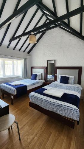 two beds in a large room with wooden floors at Gatwick Castle B&B in Horley