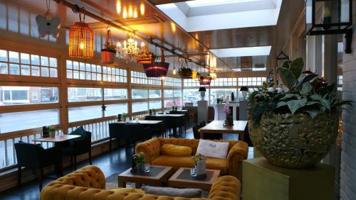 a restaurant with a couch and tables and chairs at Heeren van Noortwyck in Noordwijk aan Zee