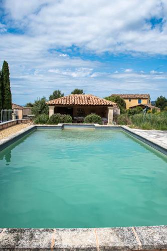 une piscine d'eau bleue devant une maison dans l'établissement Maison de la Porte des Loups dans le Ventoux, à Bédoin