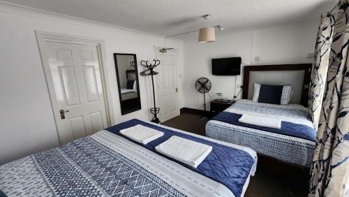 a bedroom with two beds and a television in it at Gatwick Castle B&B in Horley