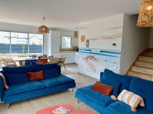 un salon avec des canapés bleus et une salle à manger dans l'établissement Lumineuse maison accès plage à pied à Plougasnou, à Plougasnou