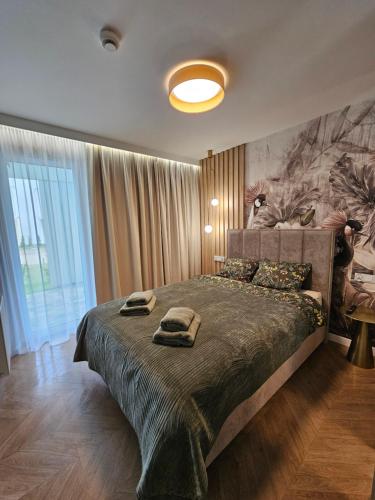 une chambre avec un grand lit et un grand tableau au mur dans l'établissement LUKSUSOWY APARTAMENT przy Plaży, à Grzybowo