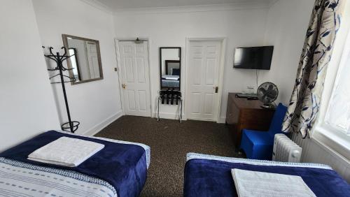 a bedroom with two beds and a chair and a desk at Gatwick Castle B&B in Horley