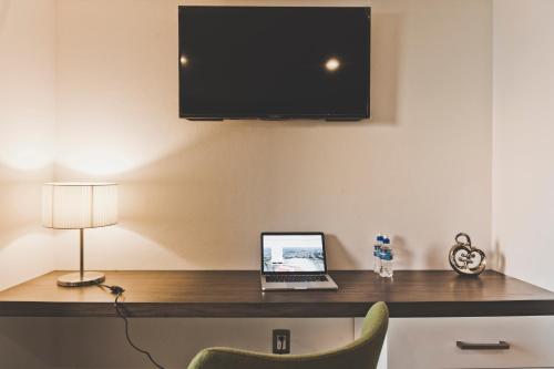 a laptop computer sitting on a desk with a tv at Hotel Platino Expo Guadalajara in Guadalajara
