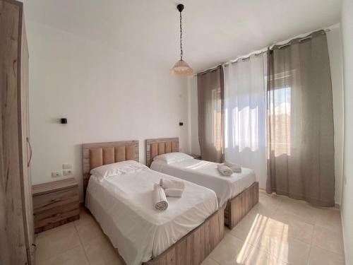 a bedroom with two beds and a large window at Appartamento Valamar Nikolla 2 camere in Hamallë
