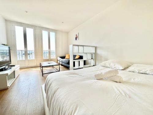 - une chambre blanche avec un grand lit et un canapé dans l'établissement Le Mozart calme et fonctionnel, à Limoges