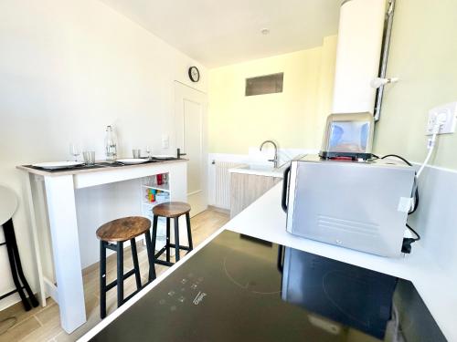 une cuisine avec un comptoir et deux tabourets dans l'établissement Le Mozart calme et fonctionnel, à Limoges