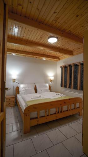 a large bed in a room with a wooden ceiling at Andreas Apartman in Keszthely