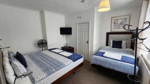 a bedroom with two beds and a flat screen tv at Gatwick Castle B&B in Horley