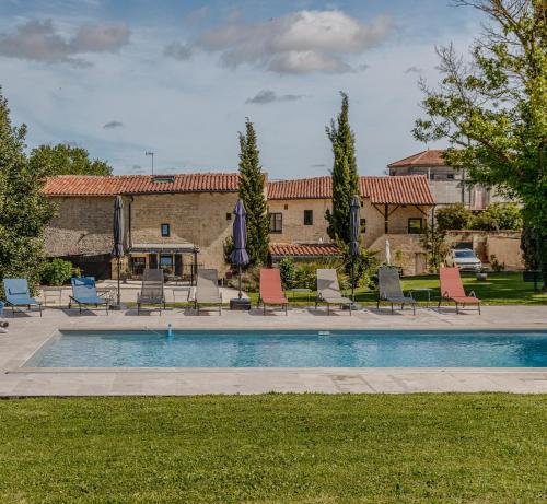 une piscine avec chaises et parasols devant un immeuble dans l'établissement Au Clos Des Dély-Gîtes 3 étoiles, à Mareuil