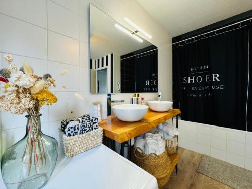 La salle de bains est pourvue de 2 lavabos et d'un vase de fleurs. dans l'établissement Loft atypique13Om2-salon de 40m2, rooftop et patio couvert dép tardif 13H-PKG gratuit privé sur place ,clim, à Bordeaux