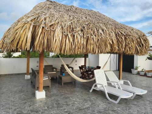 a hammock and chairs under a straw umbrella at Hostal Casa Familiar Josi in Tolú