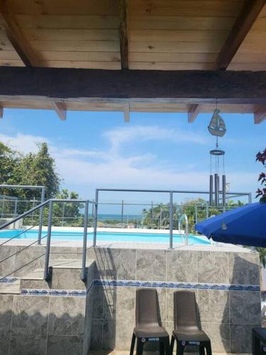 a swimming pool with two chairs and a blue umbrella at Hostal Casa Familiar Josi in Tolú