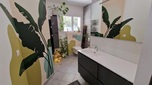 La salle de bains est pourvue d'une grande fresque murale représentant des plantes. dans l'établissement Villa contemporaine au calme entre Aix-en-Provence et Lourmarin, à Meyrargues