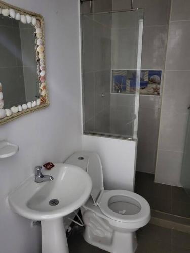 a bathroom with a sink and a toilet and a mirror at Hostal Casa Familiar Josi in Tolú