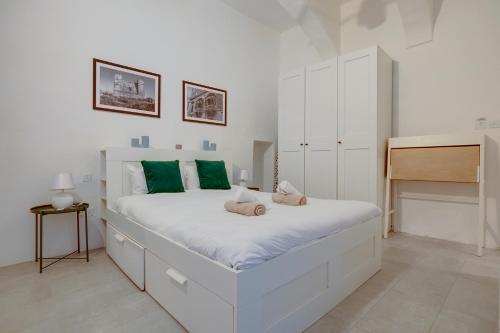a white bedroom with a large white bed with green pillows at Comfy 1 Bedroom in the Heart of Valletta in Valletta