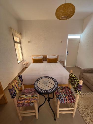 a bedroom with a bed with two chairs and a table at Le Réel Kaouki in Sidi Kaouki