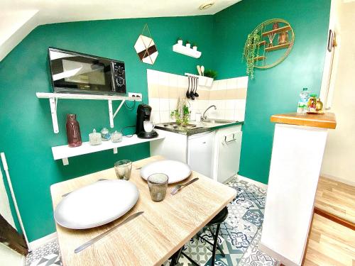 une cuisine avec des murs verts et une table avec des assiettes. dans l'établissement Le Barny studio cocooning en hyper centre, à Limoges