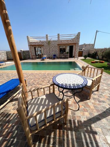 a patio with a table and chairs next to a pool at Le Réel Kaouki in Sidi Kaouki