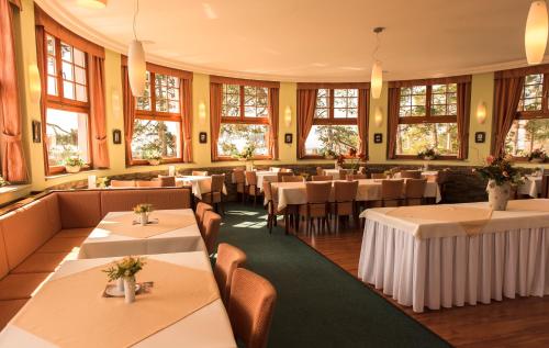 um restaurante com mesas, cadeiras e janelas em Hotel Vítkova Hora - Veitsberg em Karlovy Vary