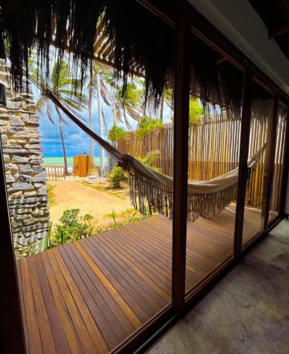 a hammock in a room with a view of the beach at Kuarasy Pousada de Charme Japaratinga in Japaratinga