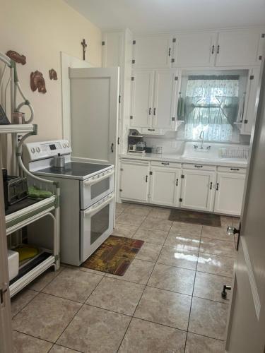 Una cocina con gabinetes blancos y un horno de estufa. en The Kaiser House, en Harper