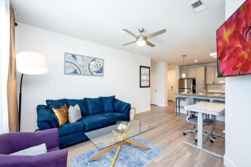 a living room with a blue couch and a table at Gated Resort Style 2BR - KING Bed, Pool Views, SPA Hot Tub, Gym, WiFi, Wash & Dry, AC, Elevators, Starbucks, EV CHRG Station, Free Parking, Pets -- IDEAL FOR Medical, Business, Relocation, Long Stays - by Moffitt Cancer Ctr, USF, River Hills Country Club in Tampa