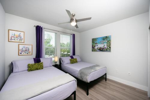 Gated Resort Style 2BR - KING Bed, Pool Views, SPA Hot Tub, Gym, WiFi, Wash & Dry, AC, Elevators, Starbucks, EV CHRG Station, Free Parking, Pets -- IDEAL FOR Medical, Business, Relocation, Long Stays - by Moffitt Cancer Ctr, USF, River Hills Country Club في تامبا: غرفة نوم بها سريرين ومروحة سقف