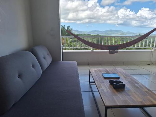 a living room with a couch and a table and a window at La plus belle vue de Ducos ! in Ducos