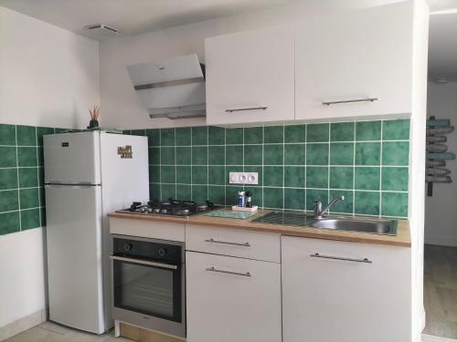 a kitchen with a white refrigerator and a sink at agréable maison de vacances en Charente-Maritime in Arvert