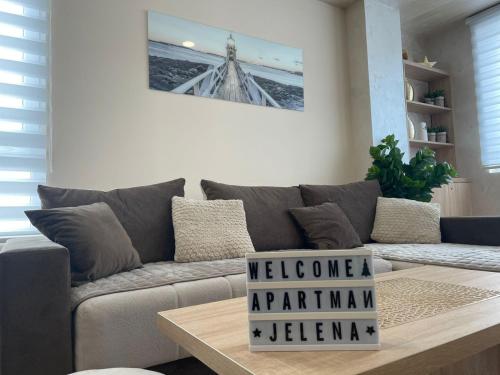 a living room with a couch with a welcome sign on a table at Apartman Jellena centar Zlatibora in Zlatibor