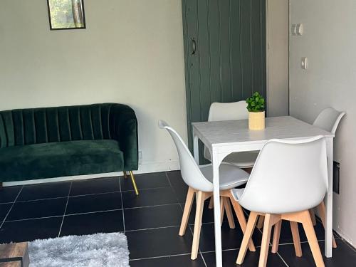 une table et des chaises dans une pièce avec un canapé vert dans l'établissement SPA hyper centre jardin, à Boulogne-sur-Mer