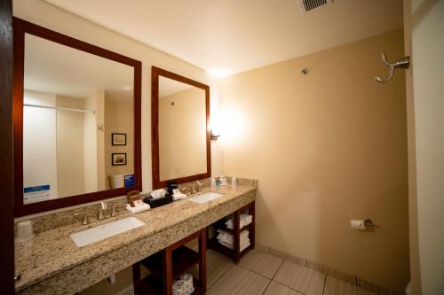 a bathroom with two sinks and a large mirror at Comfort Suites University Brookings in Brookings