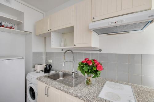 une cuisine avec un évier et un vase de roses dans l'établissement Maison de la Radio - Seine, à Paris