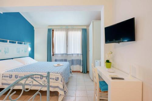 a bedroom with a bed and a desk and a tv at Il Piccolo Giardino rooms & breakfast in Villasimius