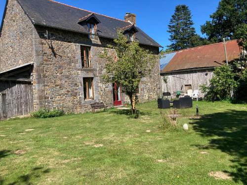 an old stone barn with a grass yard in front of it at La Fazenda in Combourg