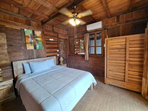 a bedroom with a bed in a room with wooden walls at Melasti Mountain Villas Amed in Amed