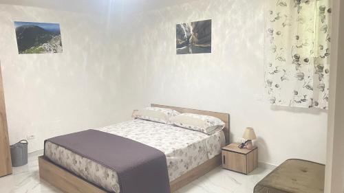 a white bedroom with a bed and some pictures on the wall at L'oasi del raganello in Civita