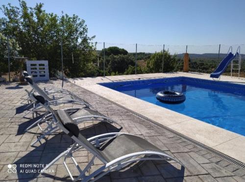 ein Swimmingpool mit Stühlen und einer Poolrutsche in der Unterkunft Villa Gracia in La Puebla de los Infantes