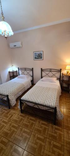 a bedroom with two beds and a lamp and two tables at stratigato in Chios
