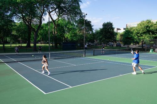 a group of people playing tennis on a tennis court at Northside FAMLYNEST Lincoln Sq 4BR 2BA 2P Rare find in Chicago