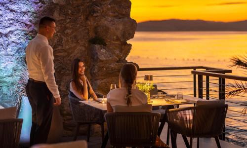 a man and two women sitting at a table in a restaurant at Magal Maradiso Hotel by Aminess in Njivice