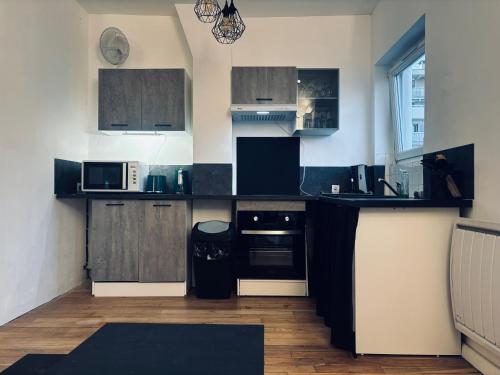 une cuisine avec des armoires et des appareils en noir et blanc dans l'établissement La maison du bonheur à Charonne, à Paris