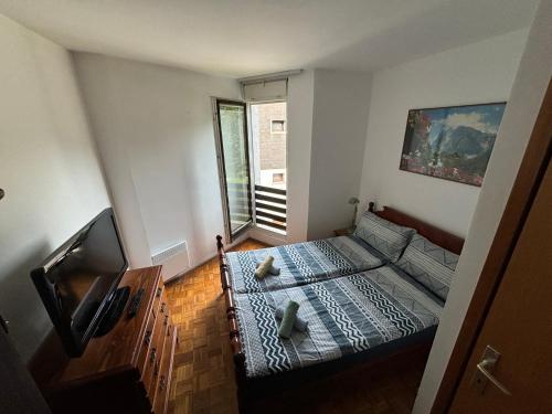 Una pequeña habitación con una cama y un televisor. en Apartma Tine, en Bovec