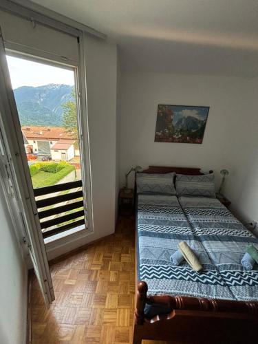 Un dormitorio con una cama y una ventana grande. en Apartma Tine, en Bovec